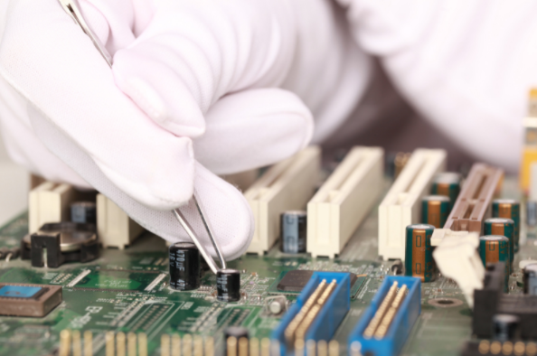 a close up of an engineer wearing white gloves and using a tweezer to work on a pcb