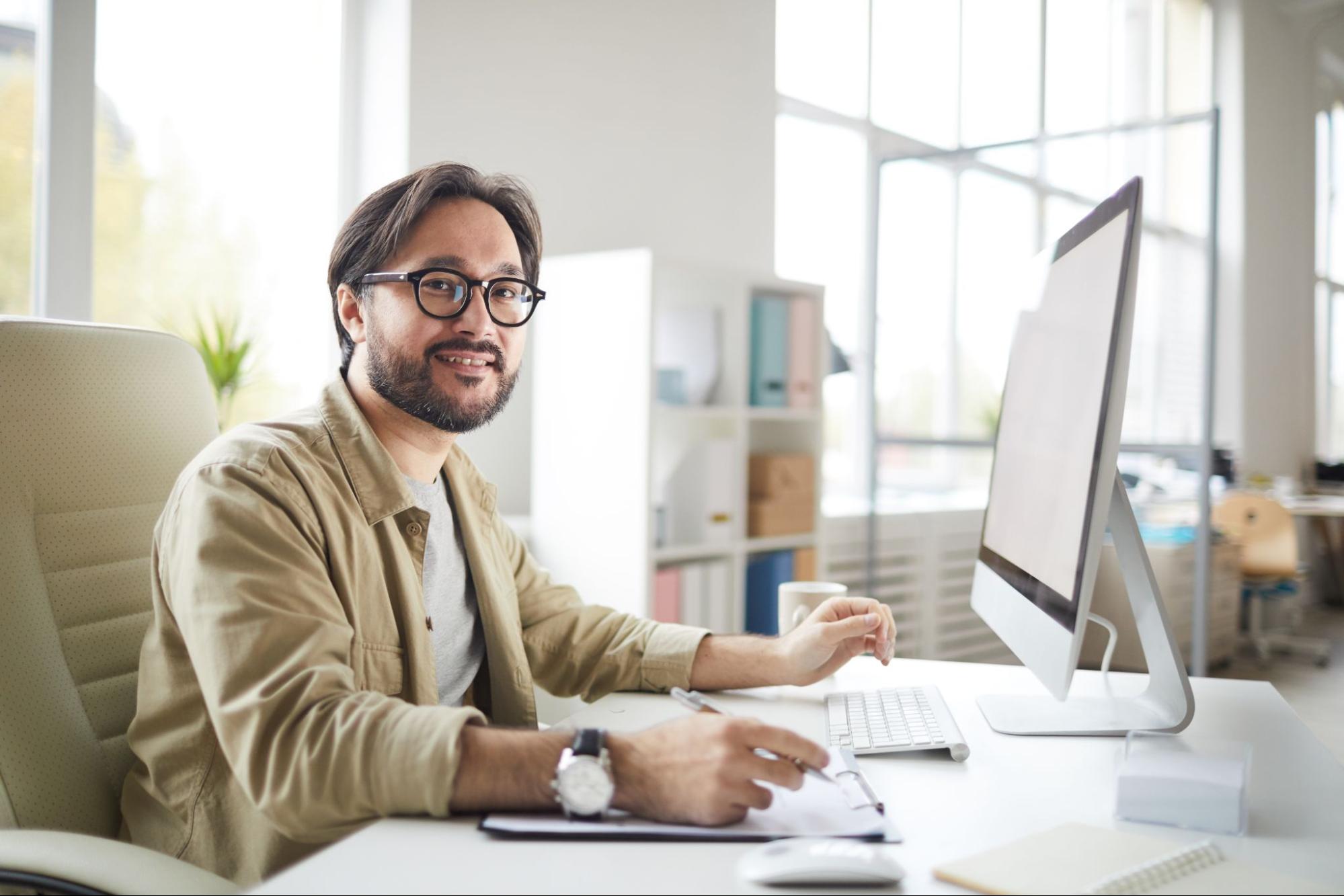 A male design engineer sits at his desk working on a design for a printed circuit board