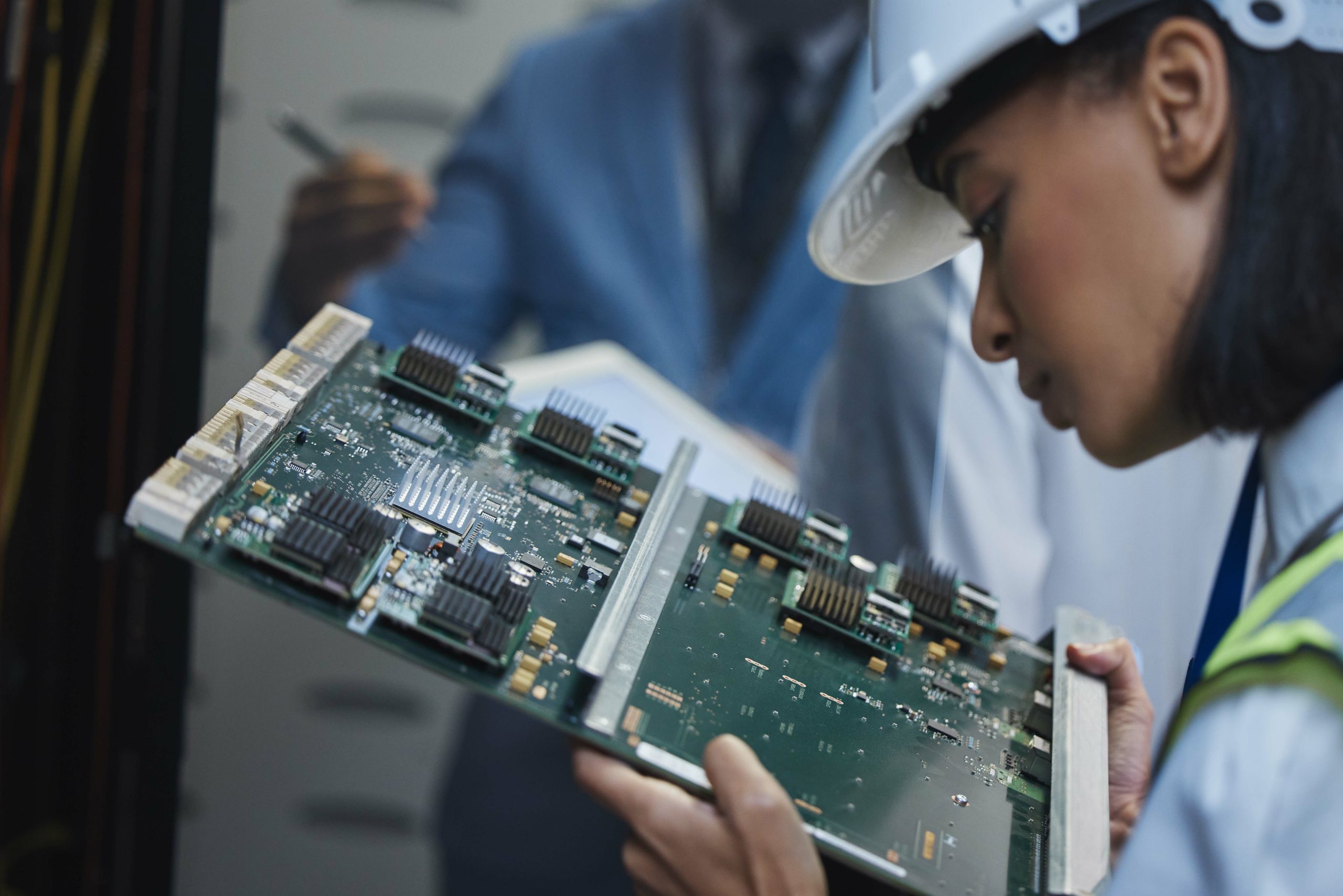 Worker doing an ITAR Compliance inspection on a circuit board
