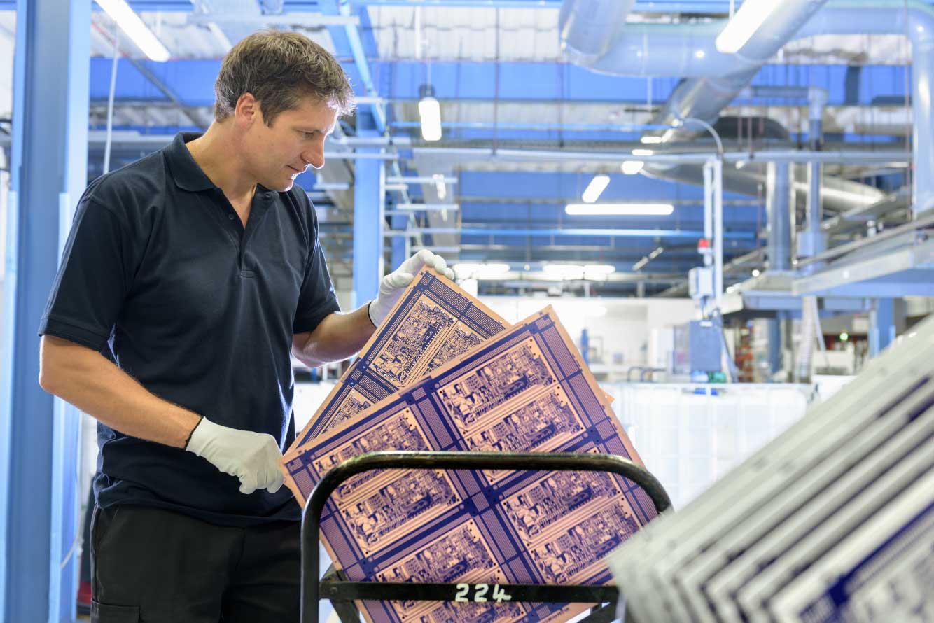 PCB Manufacturer worker inspects circuit board